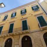 I due livelli sovrastanti presentano una serie di portafinestre con persiane verdi, modanature e timpani lineari, disposte in asse con i portali